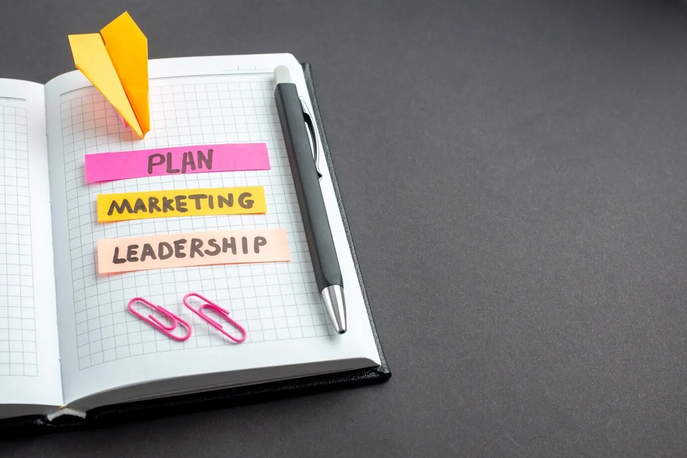 Фронтальный вид различных деловых заметок в блокноте на тёмном фоне.